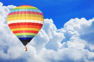 Hot air balloon on beautiful blue sky with puffy clouds