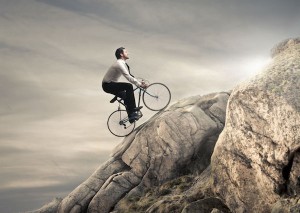 Businessman-riding-bike-up-rocky hill