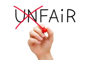 A hand making word Unfair into Fair